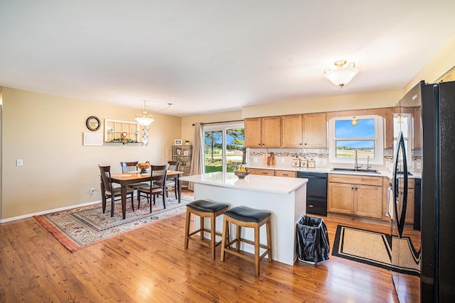 4515 S Lincoln Rd, Mount Pleasant, MI 48858 - kitchen with black appliances, light countertops, a center island, and light wood finished floors