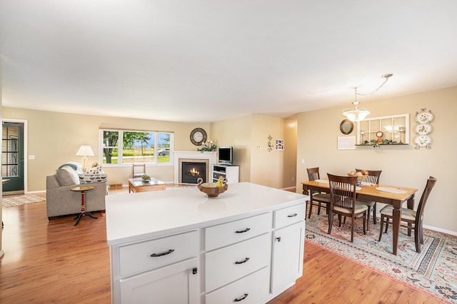 4515 S Lincoln Rd, Mount Pleasant, MI 48858 - kitchen featuring a lit fireplace, light wood-style flooring, white cabinets, and open floor plan