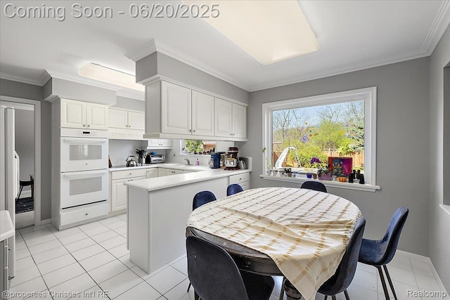 4160 Dawn Ln, West Bloomfield, MI 48323 - kitchen with double oven, a peninsula, light countertops, white cabinets, and ornamental molding