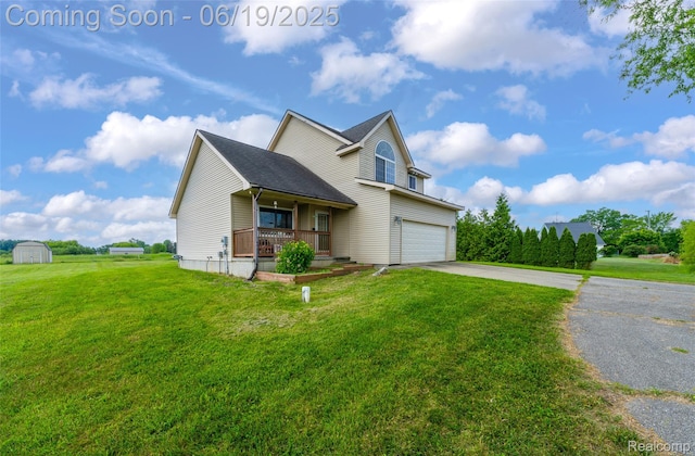 2102 Oakwood Rd, Ortonville, MI 48462 - traditional-style house featuring a porch, driveway, a front lawn, a storage shed, and an attached garage