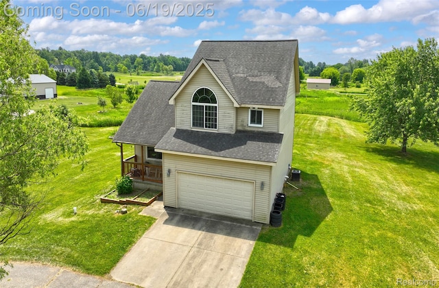 2102 Oakwood Rd, Ortonville, MI 48462 - traditional home featuring concrete driveway, a front lawn, roof with shingles, an attached garage, and view of scattered trees