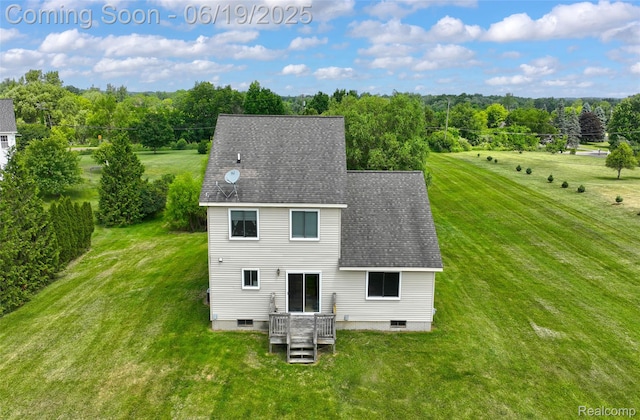 2102 Oakwood Rd, Ortonville, MI 48462 - back of property with a lawn, a shingled roof, and a view of trees