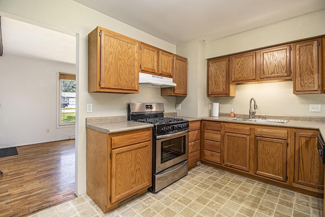 8814 S Sprinkle Rd, Portage, MI 49002 - kitchen featuring stainless steel range with gas stovetop, under cabinet range hood, brown cabinets, light countertops, and light wood finished floors