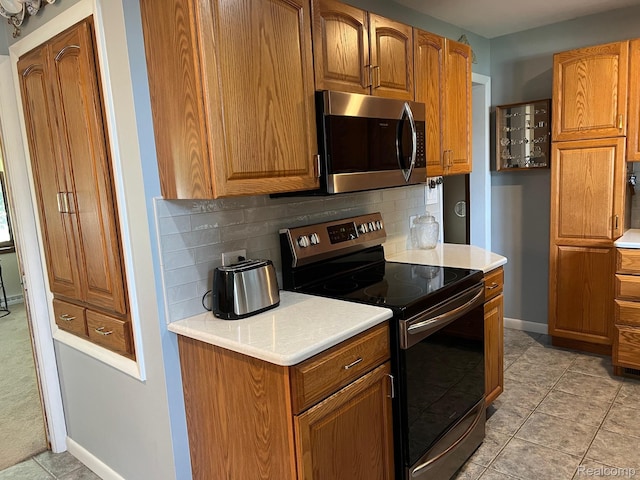 7369 Sheridan Rd, Flushing, MI 48433 - kitchen with stainless steel appliances, decorative backsplash, light countertops, and brown cabinets