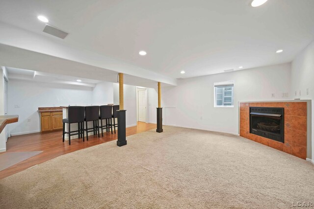 7555 Sherlock Dr, Onsted, MI 49265 - below grade area with a tile fireplace, carpet flooring, recessed lighting, bar, and wood finished floors
