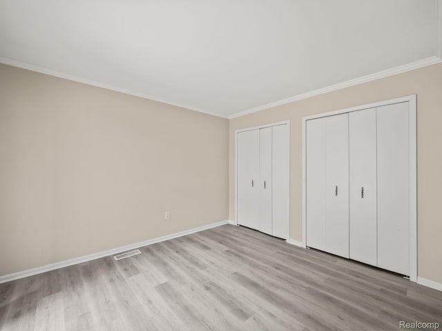 1829 Golf Ridge Dr, Bloomfield Hills, MI 48302 - unfurnished bedroom featuring multiple closets, light wood-type flooring, and ornamental molding
