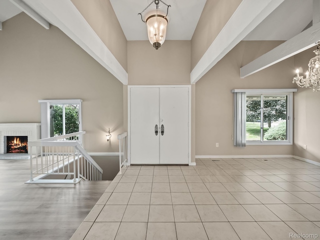 1829 Golf Ridge Dr, Bloomfield Hills, MI 48302 - foyer entrance with high vaulted ceiling, a chandelier, a fireplace, beam ceiling, and tile patterned floors