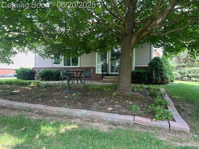 332 Asbury Ct, Highland, MI 48357 - view of property hidden behind natural elements featuring brick siding, entry steps, and a patio area