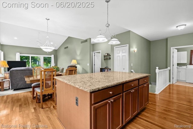 332 Asbury Ct, Highland, MI 48357 - kitchen with light wood-style floors, washer / dryer, vaulted ceiling, hanging light fixtures, and a chandelier