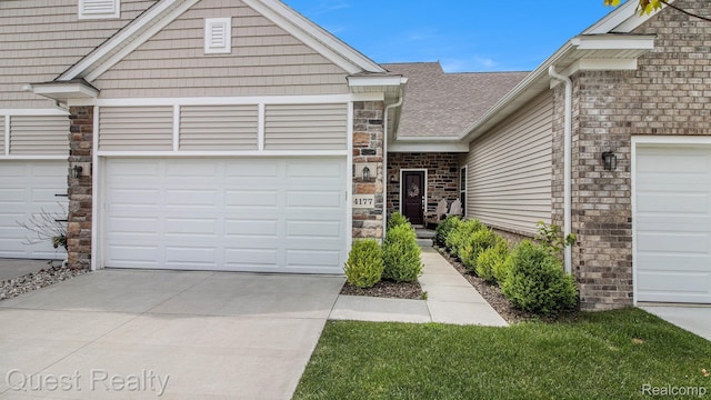 4177 Plum Village Ct, Monroe, MI 48161 - view of front facade with concrete driveway, an attached garage, stone siding, and roof with shingles