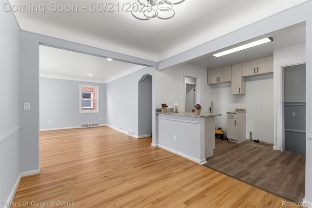 8276 Riverview St, Dearborn Heights, MI 48127 - kitchen featuring light wood finished floors, arched walkways, light stone countertops, a peninsula, and a chandelier