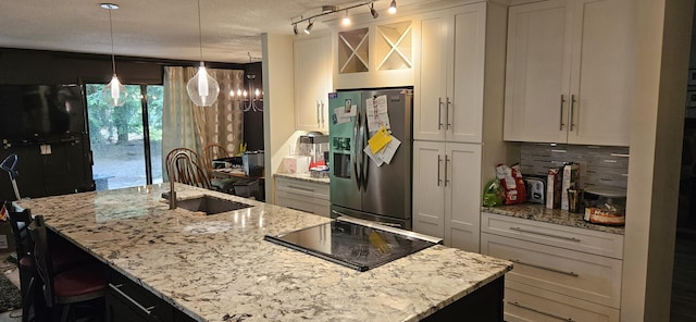 219 Walnut Woods Ct, Plainwell, MI 49080 - kitchen featuring stainless steel fridge, black electric cooktop, a kitchen island with sink, white cabinetry, and a textured ceiling
