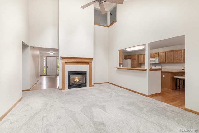 6144 Northridge Hills Dr, Brighton, MI 48116 - unfurnished living room featuring light carpet, a towering ceiling, a fireplace, and a ceiling fan