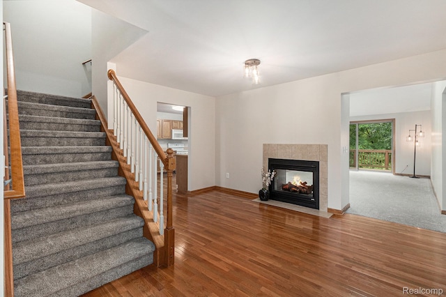6144 Northridge Hills Dr, Brighton, MI 48116 - unfurnished living room with stairway, wood finished floors, and a tiled fireplace
