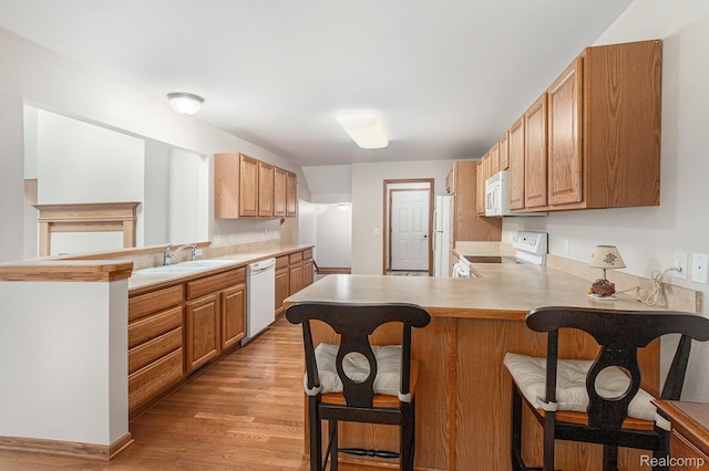 6144 Northridge Hills Dr, Brighton, MI 48116 - kitchen with white appliances, a peninsula, a breakfast bar area, light wood-style floors, and light countertops