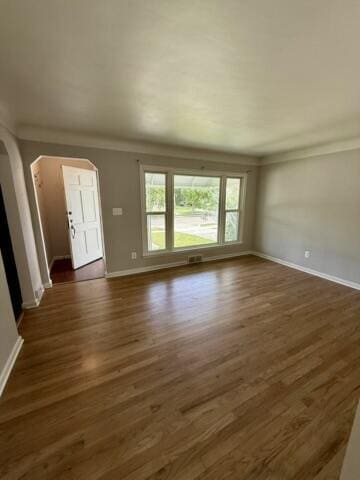 22026 Alger St, Saint Clair Shores, MI 48080 - unfurnished living room with arched walkways, dark wood finished floors, and ornamental molding