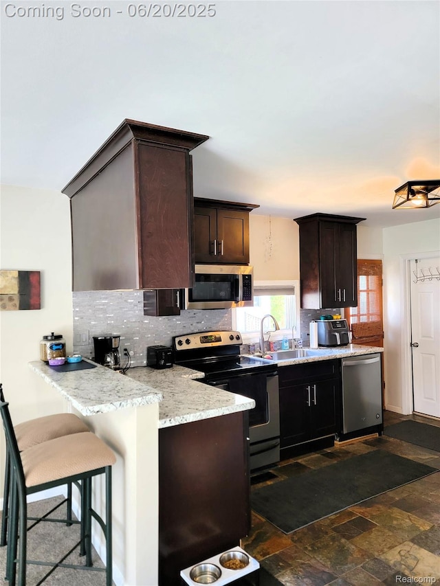 11329 E Shore Dr, Whitmore Lake, MI 48189 - kitchen with stainless steel appliances, decorative backsplash, dark brown cabinets, a peninsula, and dark stone finish floors