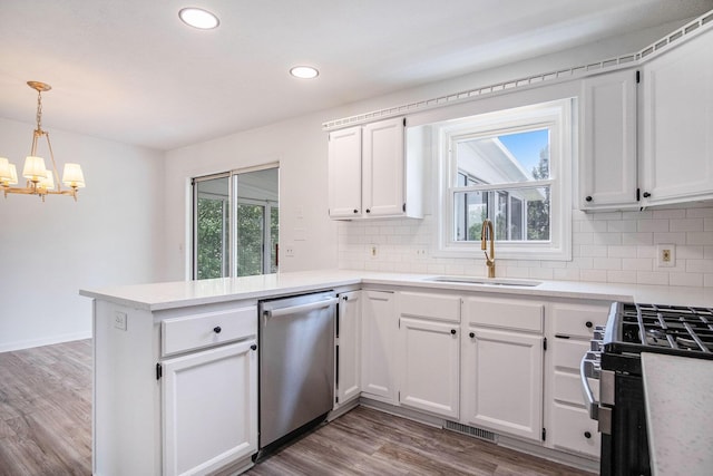 2502 Thorn Creek St SE, Kentwood, MI 49508 - kitchen featuring stainless steel appliances, a chandelier, a peninsula, tasteful backsplash, and white cabinetry