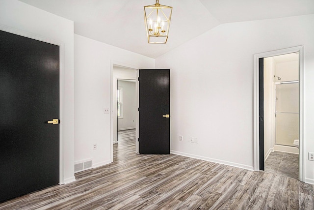 2502 Thorn Creek St SE, Kentwood, MI 49508 - unfurnished bedroom with vaulted ceiling, a chandelier, wood finished floors, and ensuite bathroom