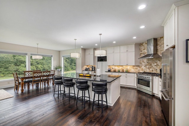 68363 Calvin Center Rd, Cassopolis, MI 49031 - kitchen featuring premium appliances, wall chimney range hood, dark countertops, a breakfast bar area, and dark wood-style flooring