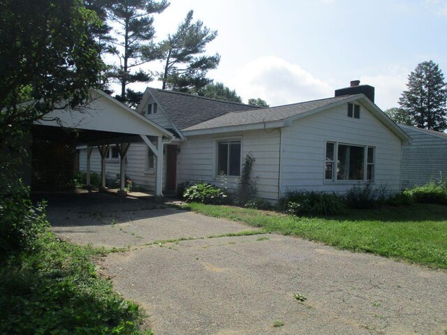 307 John St, Colon, MI 49040 - view of front of house with driveway, a chimney, roof with shingles, a carport, and a front yard