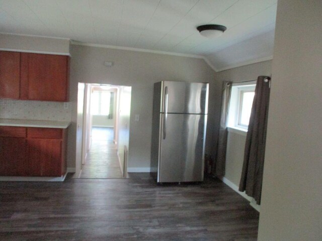 307 John St, Colon, MI 49040 - kitchen with freestanding refrigerator, brown cabinetry, dark wood-style floors, vaulted ceiling, and crown molding