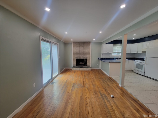 3136 Alden Dr, Sterling Heights, MI 48310 - unfurnished living room with light wood-style floors, recessed lighting, a brick fireplace, and crown molding