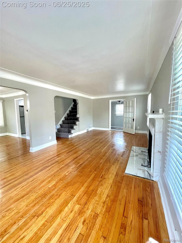 10351 Kramer, Detroit, MI 48204 - unfurnished living room with a fireplace, stairs, light wood finished floors, arched walkways, and healthy amount of natural light