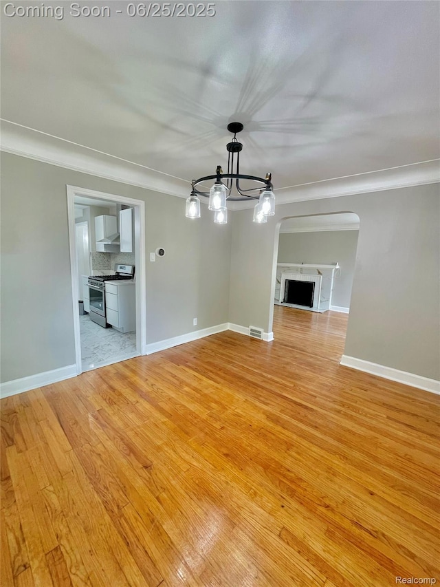 10351 Kramer, Detroit, MI 48204 - empty room with crown molding, light wood-style flooring, arched walkways, and a chandelier