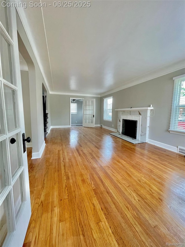 10351 Kramer, Detroit, MI 48204 - unfurnished living room with a brick fireplace, light wood-style floors, arched walkways, and crown molding