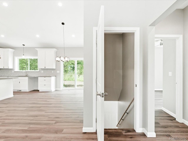 9711 Crawford, Columbus, MI 48063 - kitchen with light wood finished floors, light countertops, white cabinetry, decorative light fixtures, and backsplash
