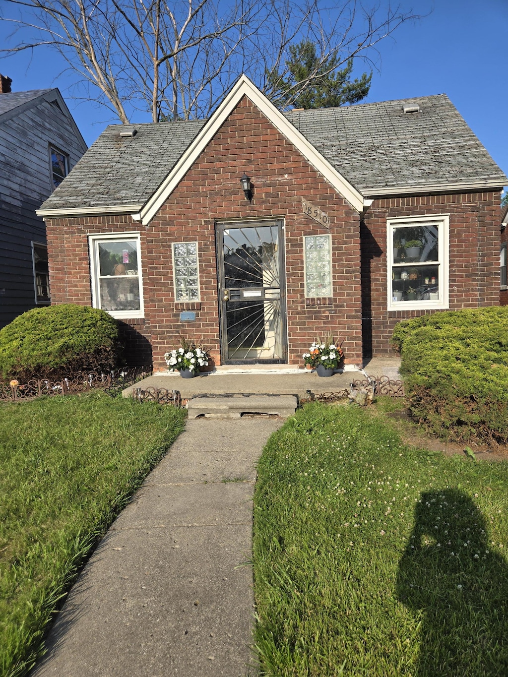 18510 Alcoy Ave, Detroit, MI 48205 - view of front of house with brick siding, a front lawn, and a shingled roof