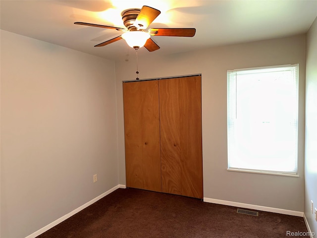 7841 Horseshoe Creek Ct, Whitmore Lake, MI 48189 - unfurnished bedroom featuring a closet, dark carpet, and a ceiling fan