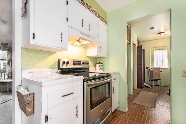 1538 Sheridan Ave, Niles, MI 49120 - kitchen featuring stainless steel range with electric stovetop, under cabinet range hood, light countertops, white cabinets, and brick patterned flooring