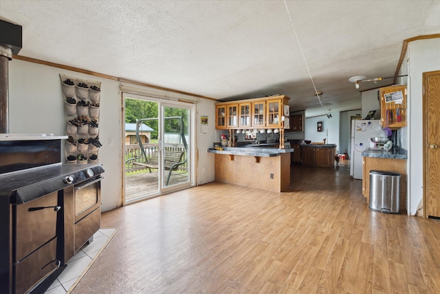 21576 220th Ave, Tustin, MI 49688 - kitchen featuring a peninsula, light wood-type flooring, crown molding, a breakfast bar area, and glass insert cabinets
