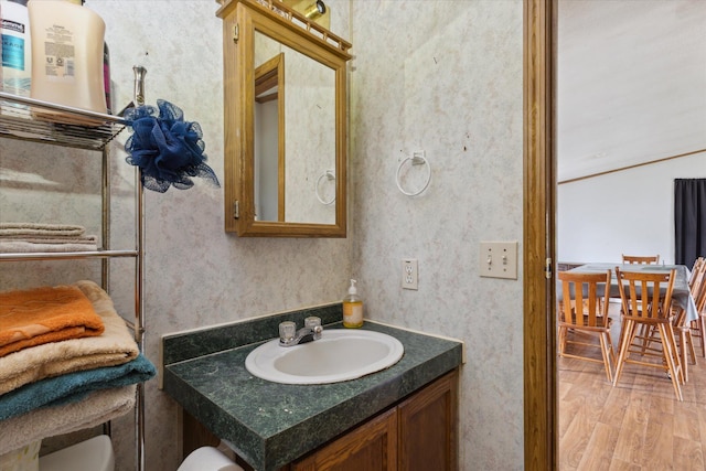 21576 220th Ave, Tustin, MI 49688 - half bathroom with vanity, wood finished floors, and wallpapered walls