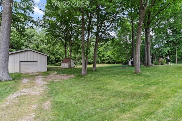 13256 Pine Valley Dr, Clio, MI 48420 - view of grassy yard featuring dirt driveway, a shed, and a detached garage