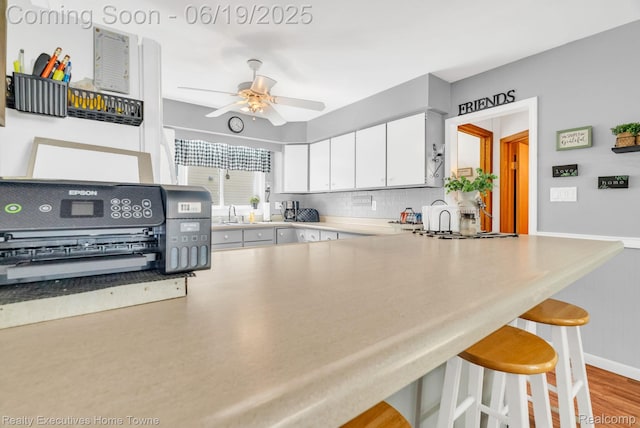 727 Minnie St, Port Huron, MI 48060 - kitchen with a ceiling fan, tasteful backsplash, a peninsula, a kitchen breakfast bar, and white cabinets