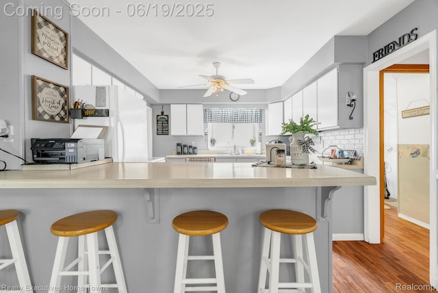 727 Minnie St, Port Huron, MI 48060 - kitchen with a ceiling fan, white cabinets, light wood-style flooring, and a peninsula