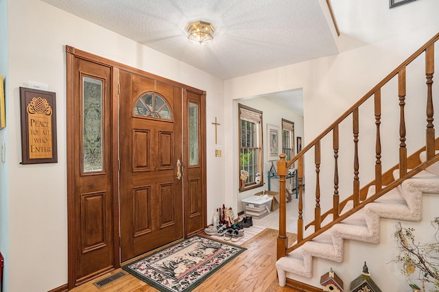 4686 Doug Dr, Whitehall, MI 49461 - entryway with light wood-style flooring, stairs, and a textured ceiling