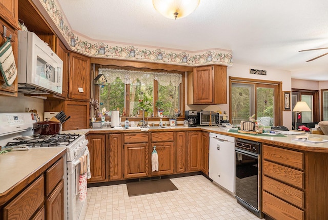 4686 Doug Dr, Whitehall, MI 49461 - kitchen with white appliances, brown cabinetry, plenty of natural light, and a peninsula
