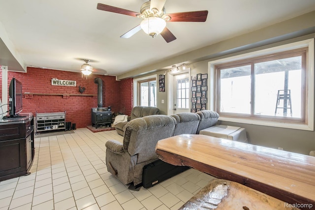 12109 Shaffer Rd, Davisburg, MI 48350 - living area featuring a wood stove, brick wall, light tile patterned flooring, and ceiling fan