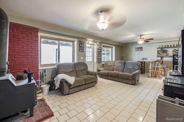 12109 Shaffer Rd, Davisburg, MI 48350 - living room featuring a wood stove, tile patterned flooring, ceiling fan, and healthy amount of natural light