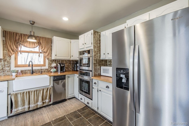 12109 Shaffer Rd, Davisburg, MI 48350 - kitchen with appliances with stainless steel finishes, butcher block countertops, decorative backsplash, white cabinetry, and dark tile patterned floors