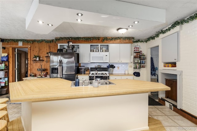 5045 Baldwin Rd, Swartz Creek, MI 48473 - kitchen with white microwave, stainless steel refrigerator with ice dispenser, range with gas cooktop, white cabinetry, and wood counters