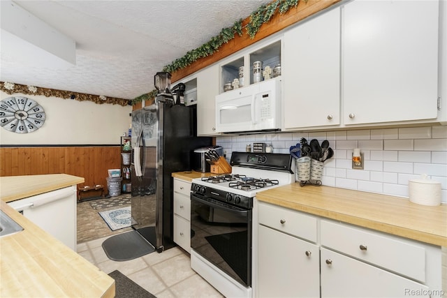 5045 Baldwin Rd, Swartz Creek, MI 48473 - kitchen featuring range with gas cooktop, white microwave, a textured ceiling, white cabinetry, and tasteful backsplash