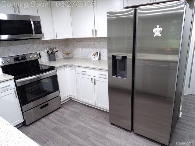 11306 W St, Grand Blanc, MI 48439 - kitchen with stainless steel appliances, white cabinetry, backsplash, light stone countertops, and light wood finished floors