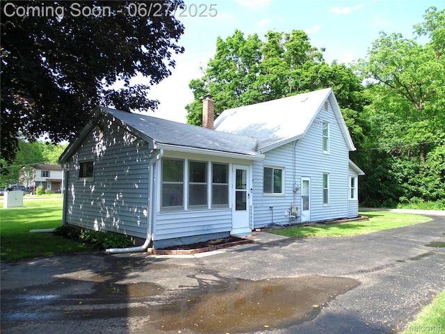 11306 W St, Grand Blanc, MI 48439 - view of front of house with a chimney, a front lawn, and a shingled roof