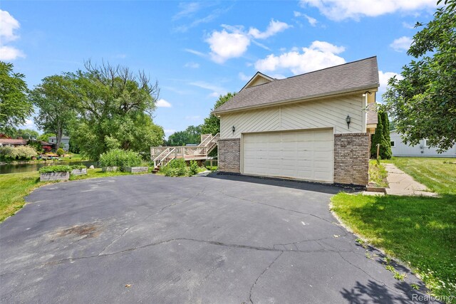 969 Bogie Lake Rd, White Lake, MI 48383 - view of home's exterior with brick siding, driveway, a water view, and stairs