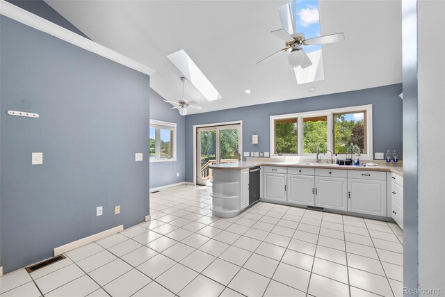 969 Bogie Lake Rd, White Lake, MI 48383 - kitchen featuring vaulted ceiling, a skylight, stainless steel dishwasher, white cabinetry, and light countertops